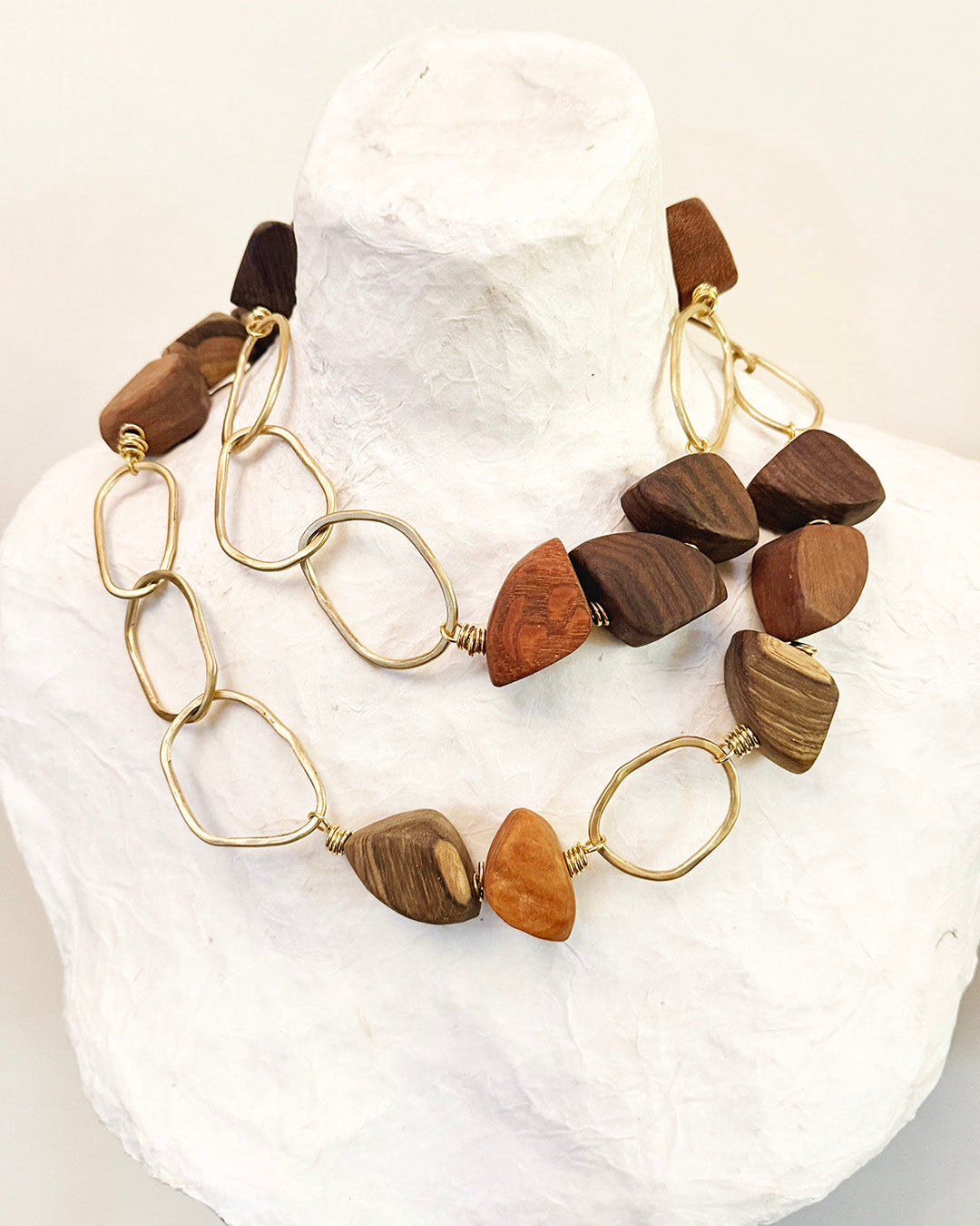 Necklace with wooden beads on a mannequin head against a white background
