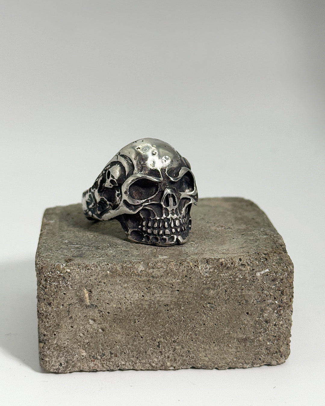 Silver skull ring on a concrete block with a gray background