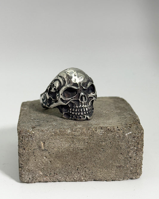 Silver skull ring on a concrete block with a gray background
