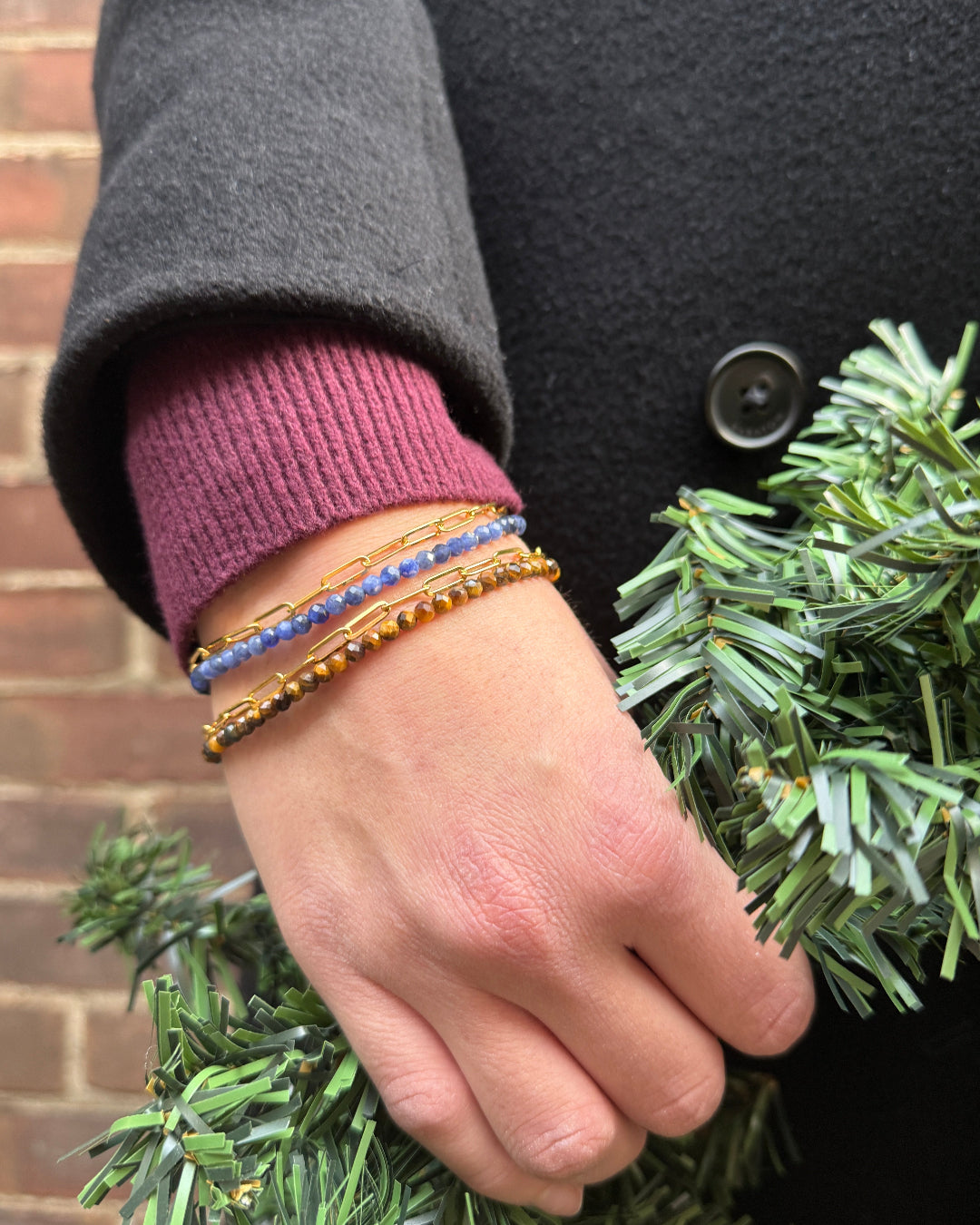 Hand wearing multiple bracelets on a blurred background