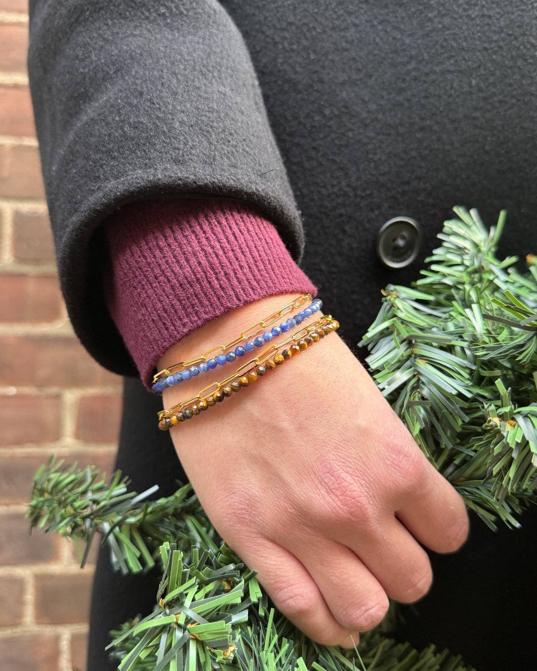 Hand wearing multiple bracelets on a dark background