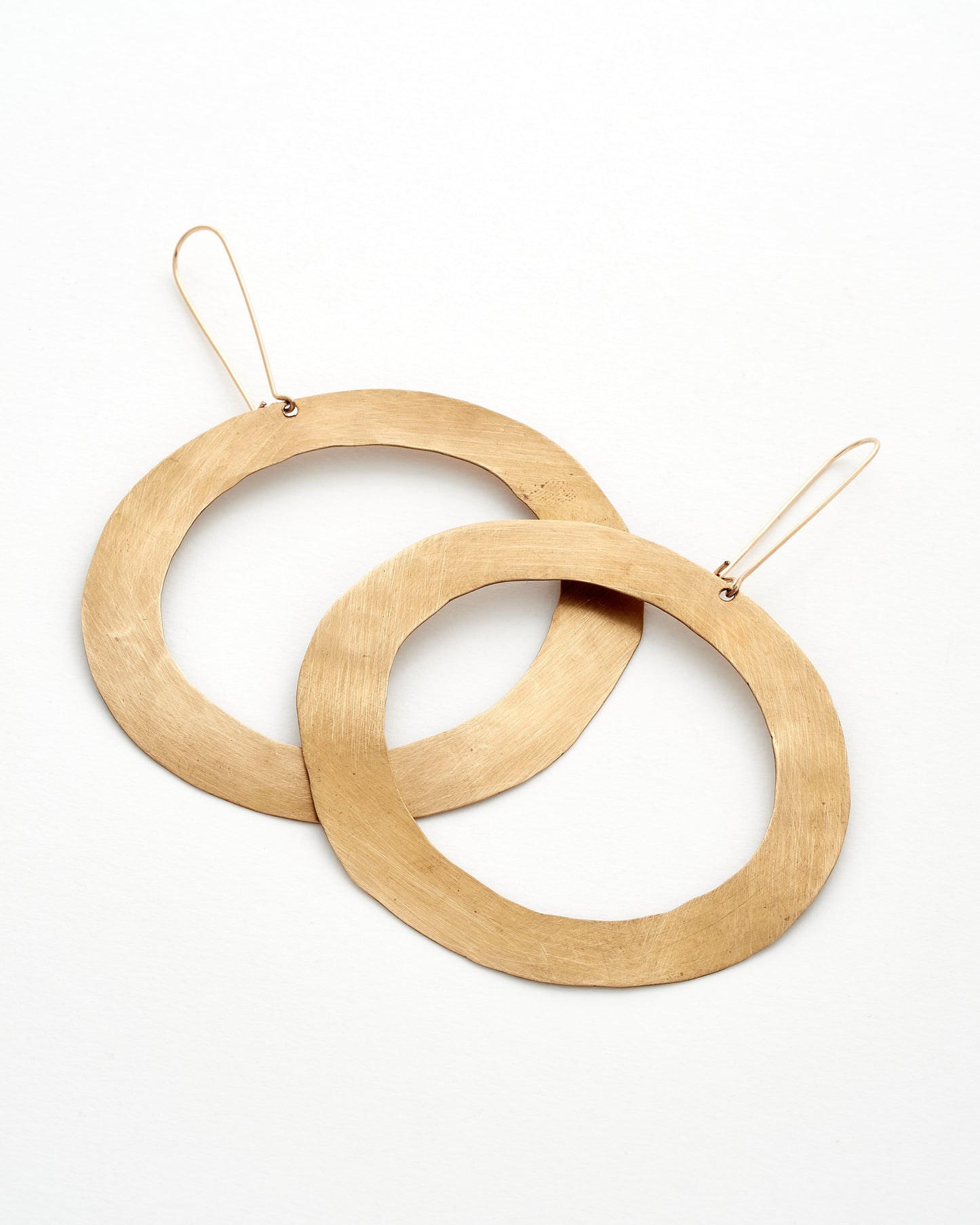 Two modern bronze hoop earrings on a white background