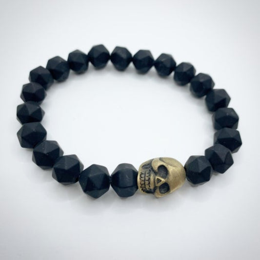 Black beaded bracelet with a gold skull charm on a white background