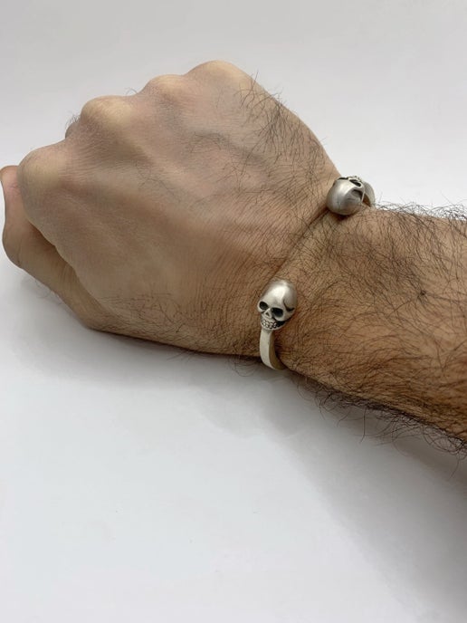 Hand wearing a bracelet with skull details on a white background