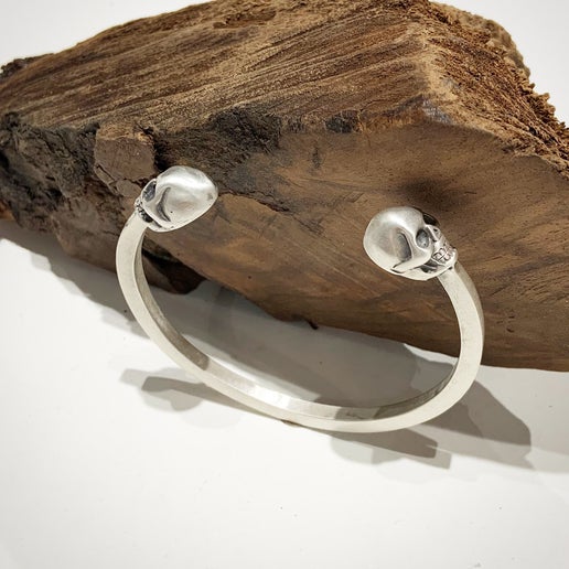 Silver skull-themed bracelet on a wooden surface
