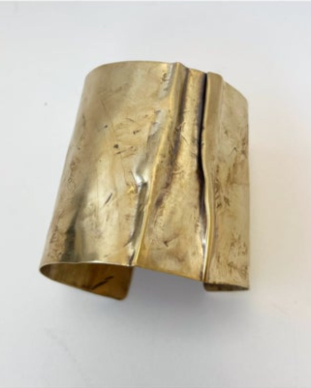 Gold cuff bracelet on a light gray background