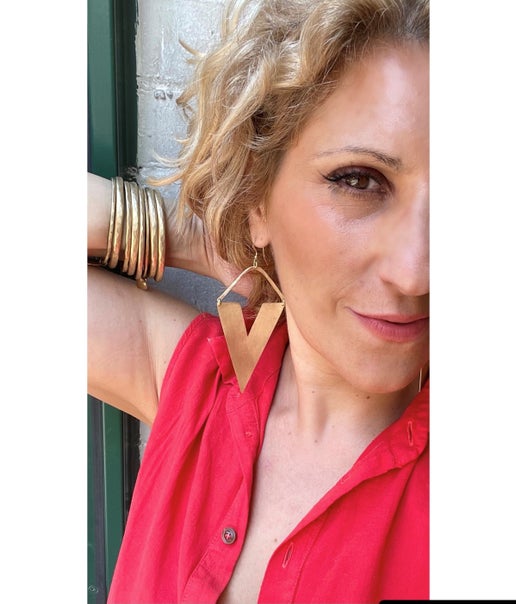 Woman wearing a red shirt with a gold inverted triangle-shaped earring and bracelets.