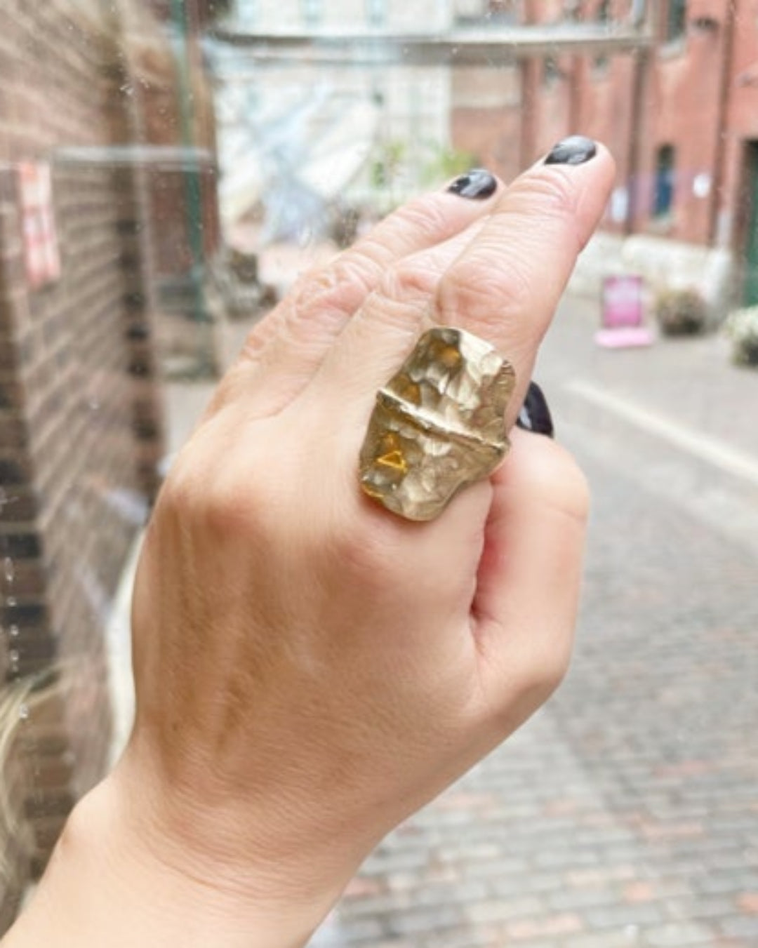 Hand wearing a large, uniqu  bronze ring with a blurred background