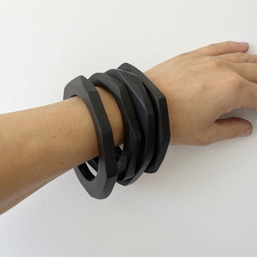 Hand wearing four ebony bracelets on a white background