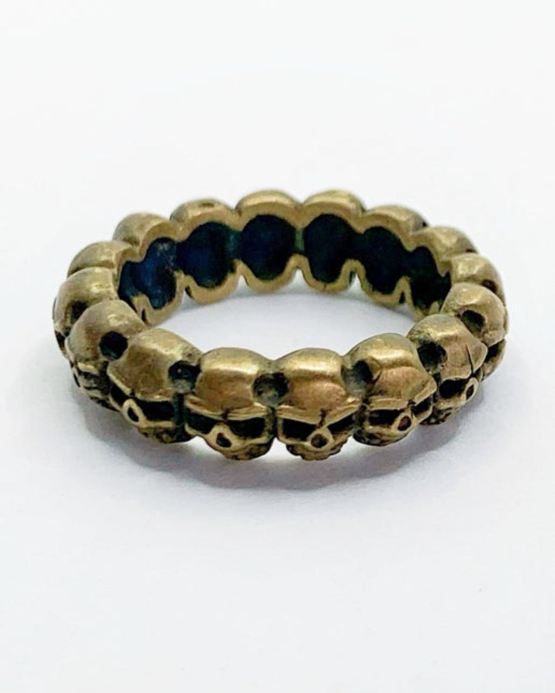 Gold ring with skull designs on a white background