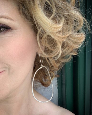 Close-up of a woman wearing a large hoop earring with a blurred background