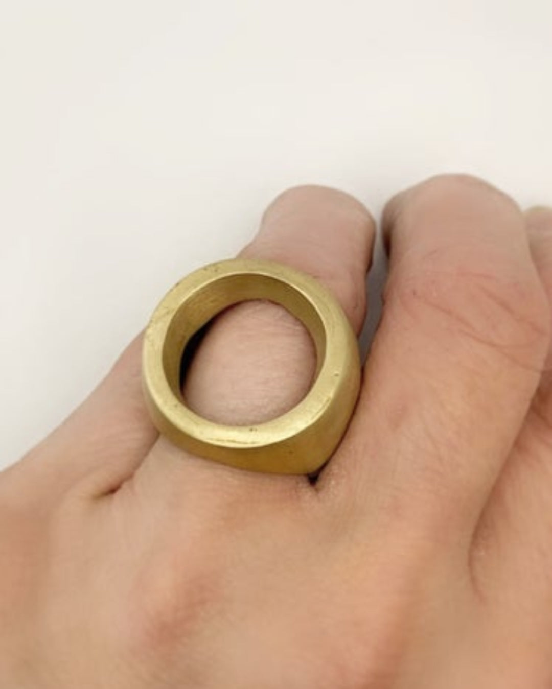 Gold ring being worn on a finger against a white background