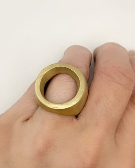 Gold ring being worn on a finger against a white background