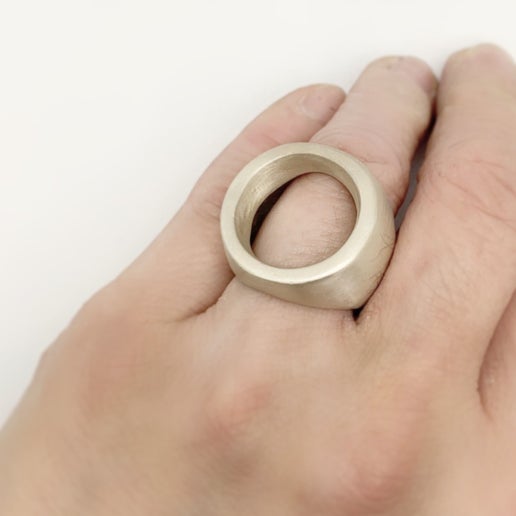 Hand wearing a large silver ring on a white background