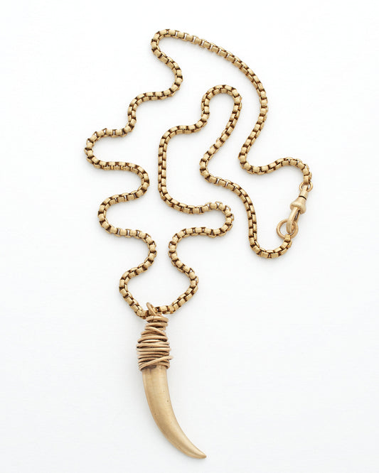 Gold necklace with a horn shaped pendant on a white background