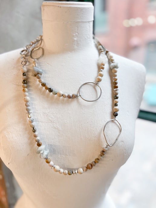 Necklace with beads and circular pendants on a mannequin bust.