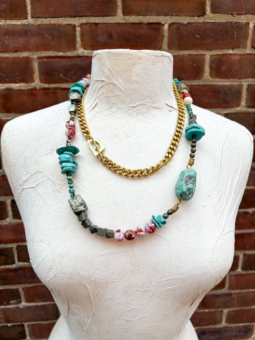 Necklace with colorful beads on a mannequin against a brick wall