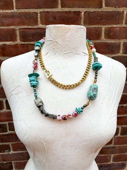 Necklace with colorful beads on a mannequin against a brick wall