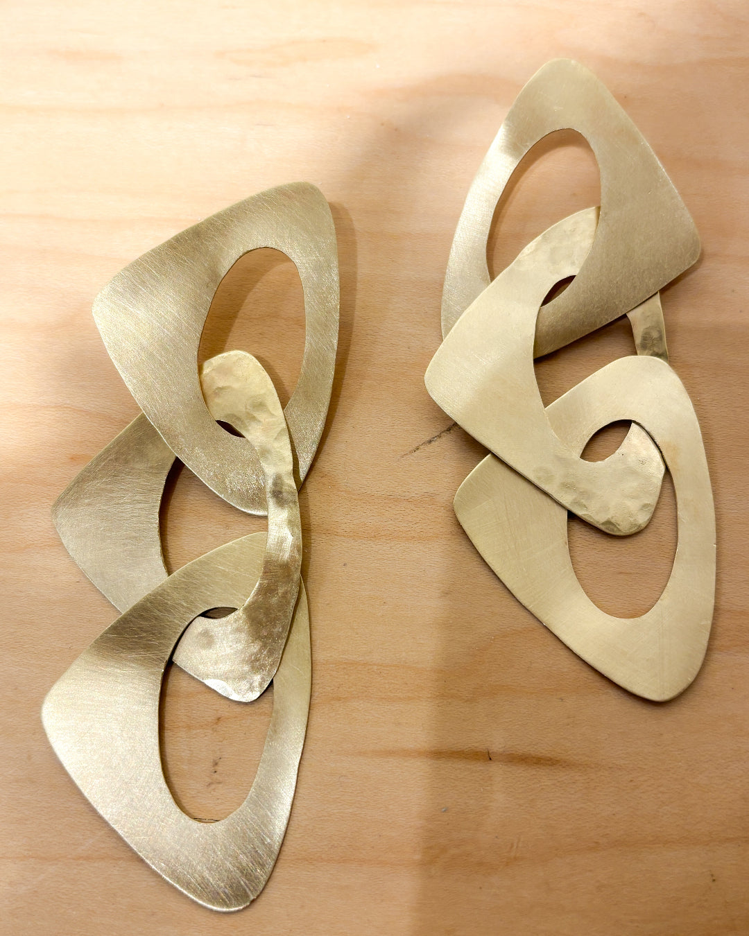 Pair of gold geometric earrings on a wooden surface