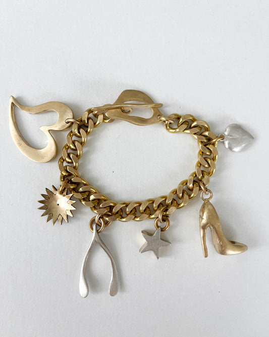 Gold chain bracelet with various bronze and silver charms on a white background