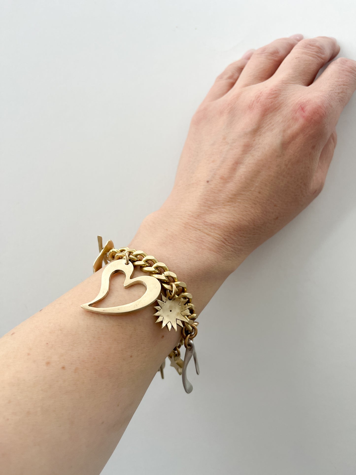 Gold bracelet with charms on a wrist against a white background
