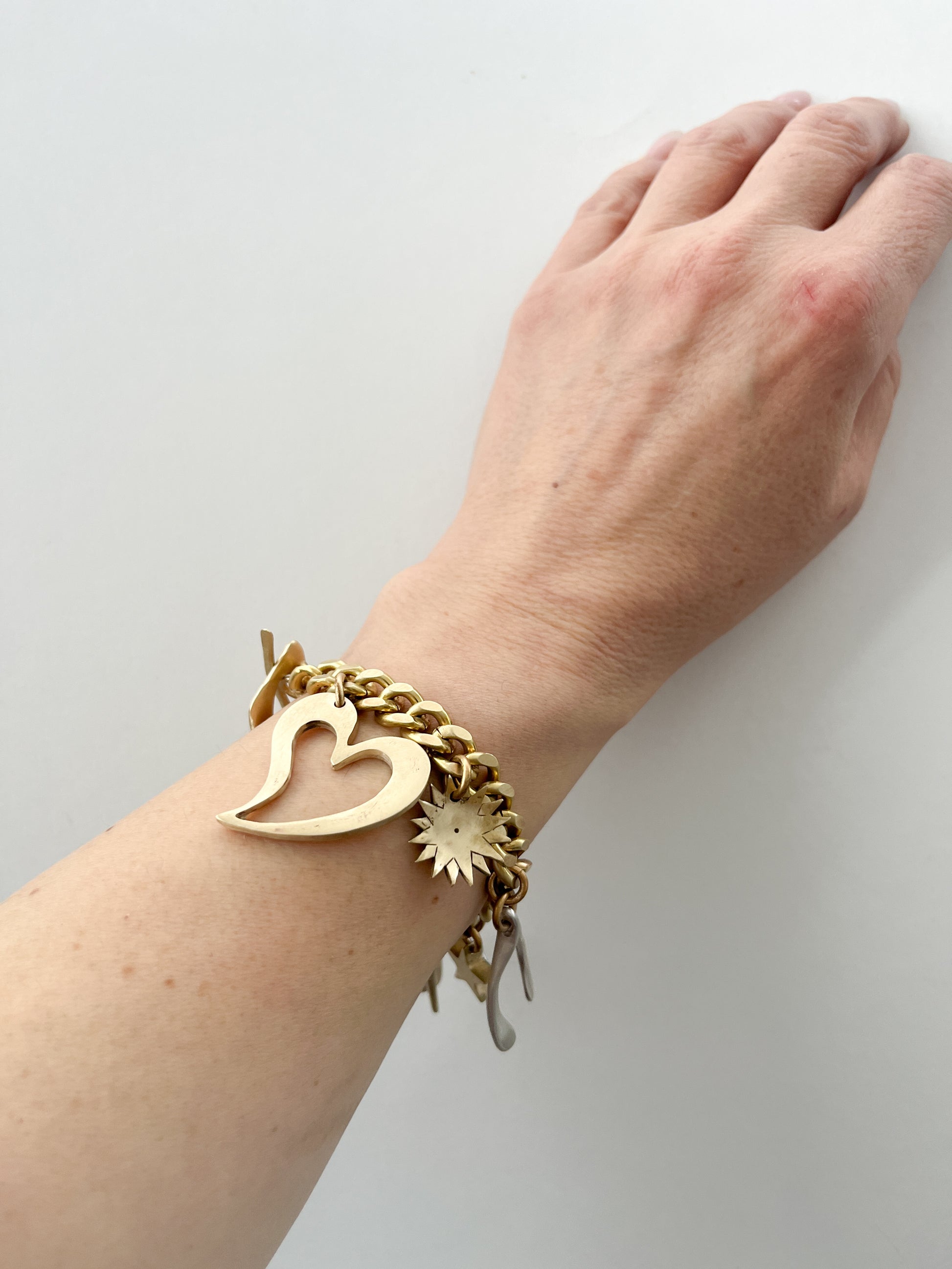 Gold bracelet with charms on a wrist against a white background