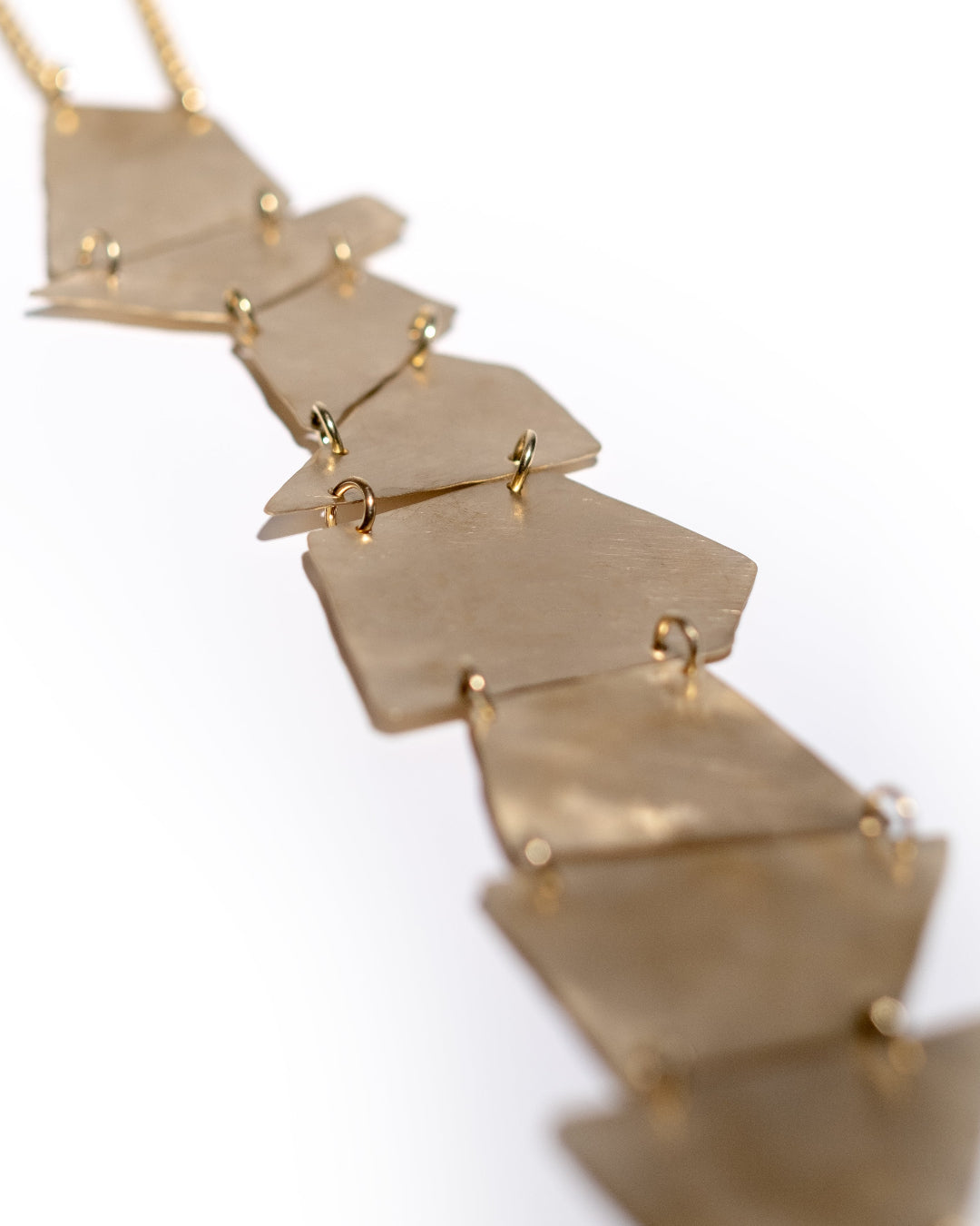 Gold necklace with geometric pendants on a white background