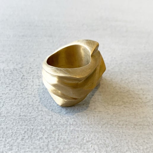 Gold ring with a unique design on a light gray background