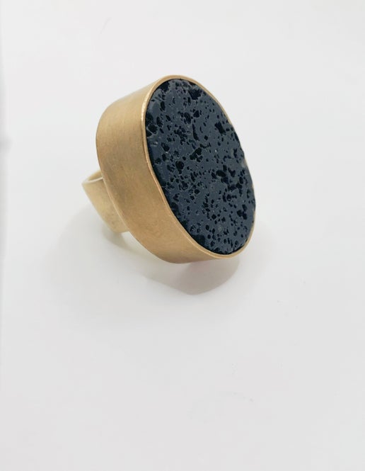 Gold ring with an oval black stone on a white background