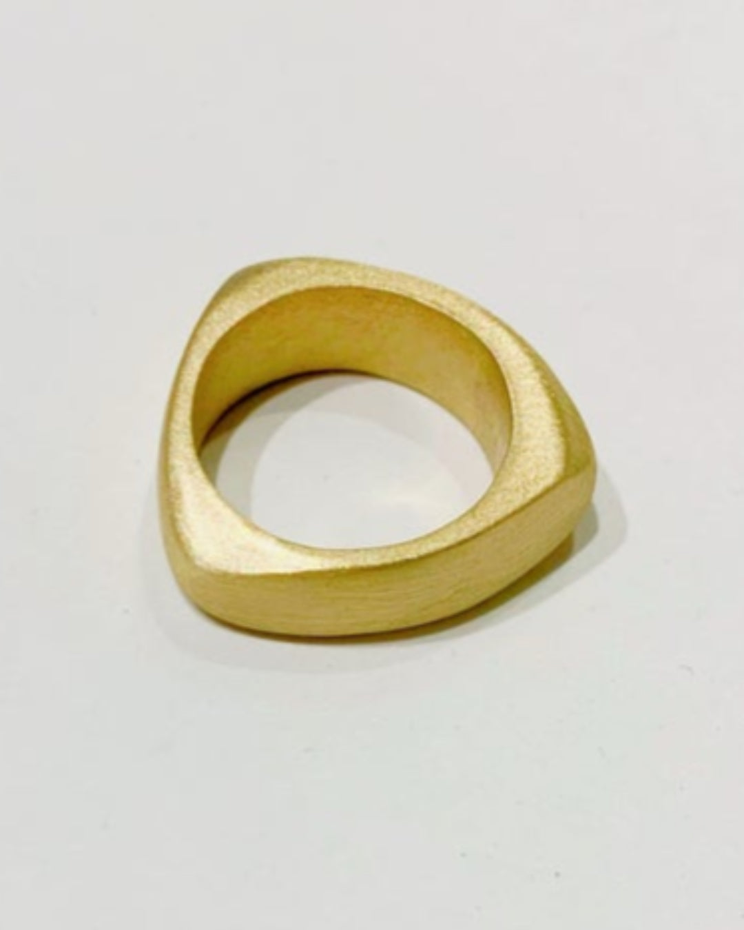Gold ring with a geometric design on a light gray background