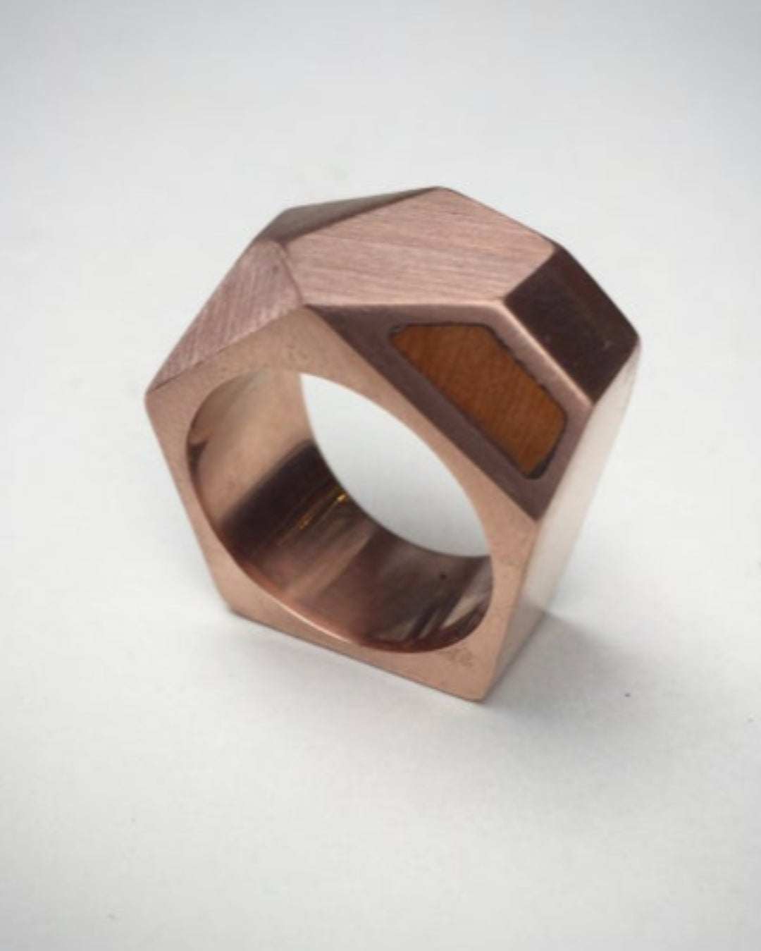 Geometric rose gold ring with wooden inlay on a white background