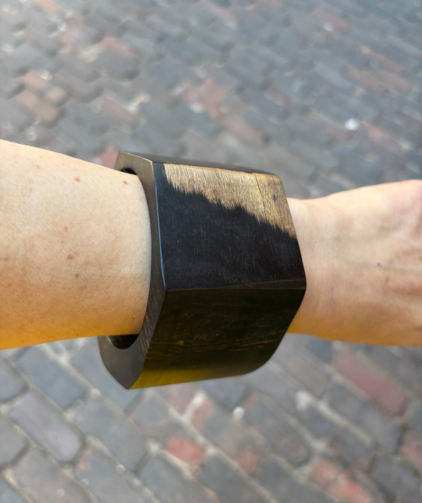 Ebony bracelet on a wrist with a blurred pavement background