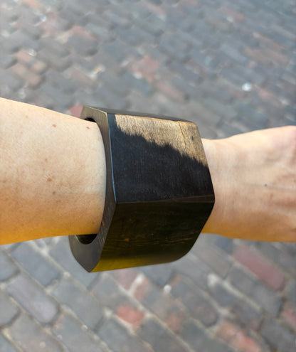 Ebony bracelet on a wrist with a blurred pavement background