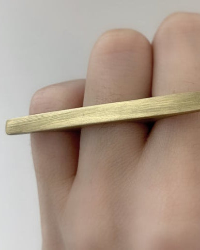 Gold multi-finger ring on a hand against a white background