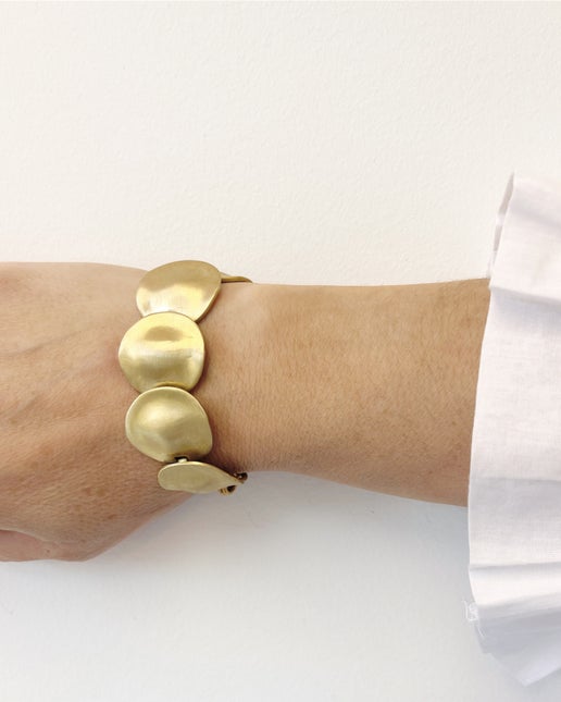 Gold bracelet on a wrist with a white background