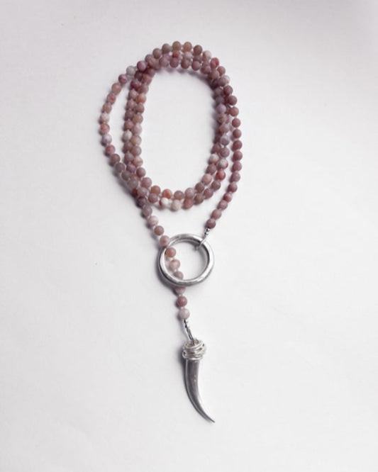 Necklace with pink beads and a silver pendant on a light gray background