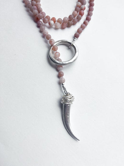 Necklace with pink beads and silver pendant on a white background