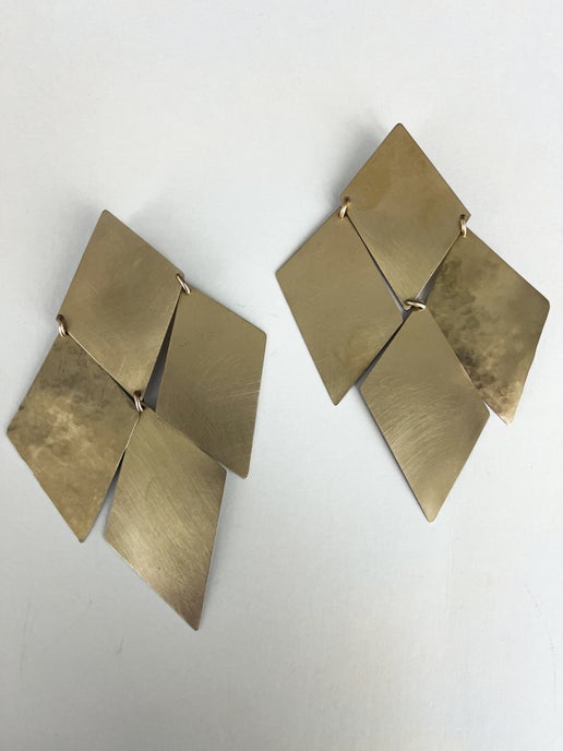 Pair of gold geometric earrings on a light gray background