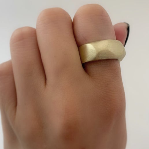 Gold ring on a person's finger against a white background