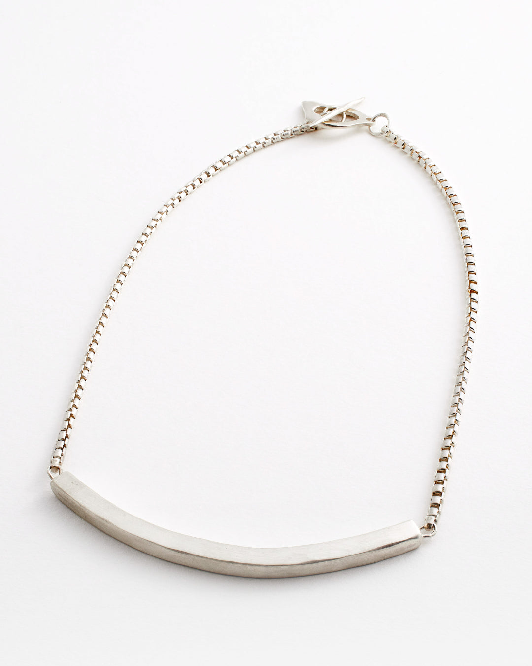 Silver necklace with a curved pendant on a white background