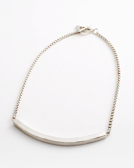 Silver necklace with a curved pendant on a white background