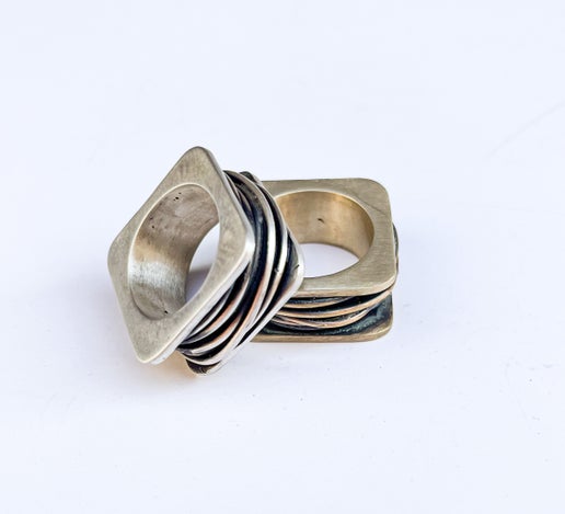 One silver ring and one bronze ring with geometric design on a white background