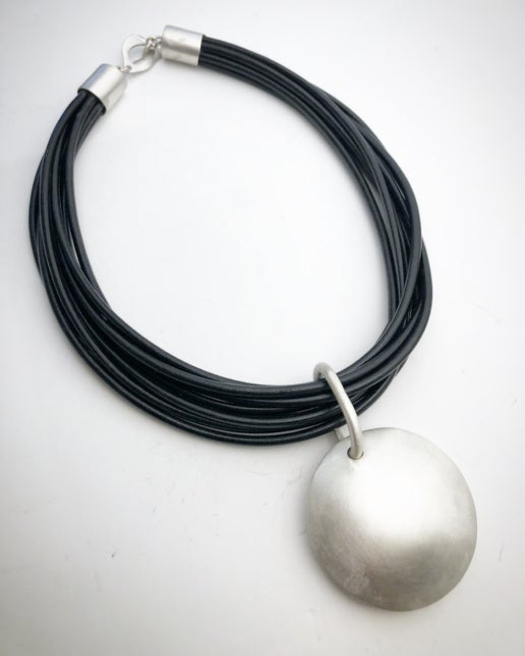 Multistrand black leather necklace with silver pendant on a white background