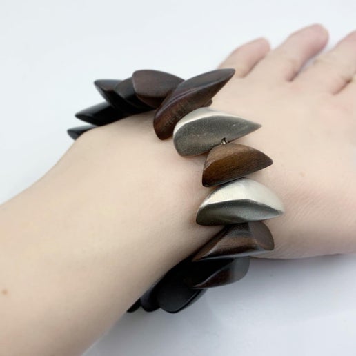 Wooden bracelet with pebble-shaped pieces on a wrist against a white background