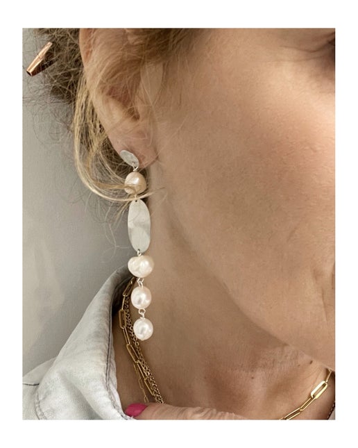 Pearl earrings worn by a person with a neutral background