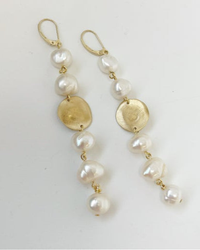 Pearl and gold disc drop earrings on a light gray background