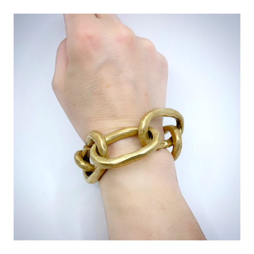 Wrist wearing a gold link bracelet on a light background