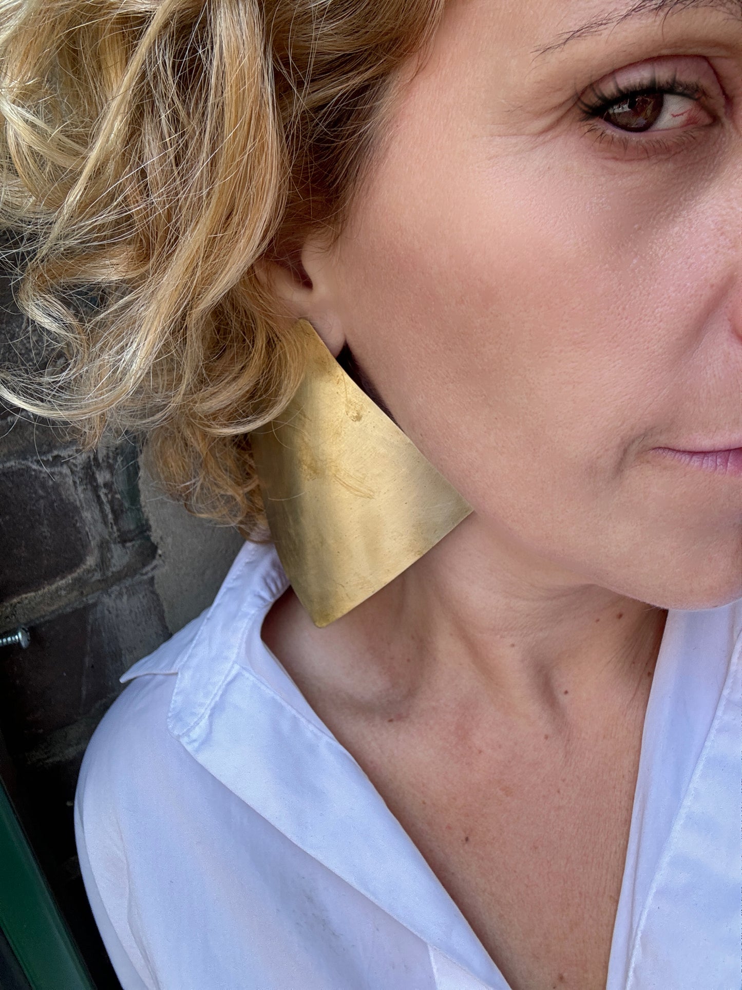 Close-up of a person wearing a large gold curved earring.