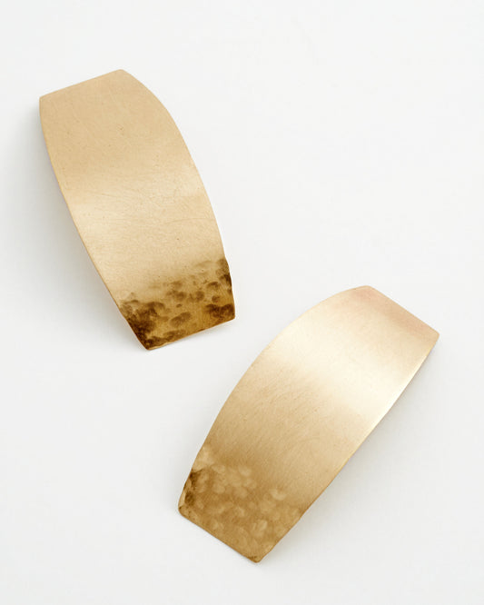 Curved rectangular bronze earrings on a light background.