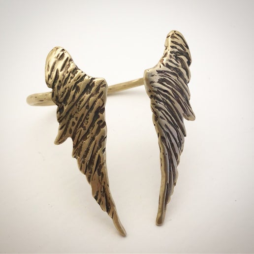 Bronze cuff with angel wing detail on a white background